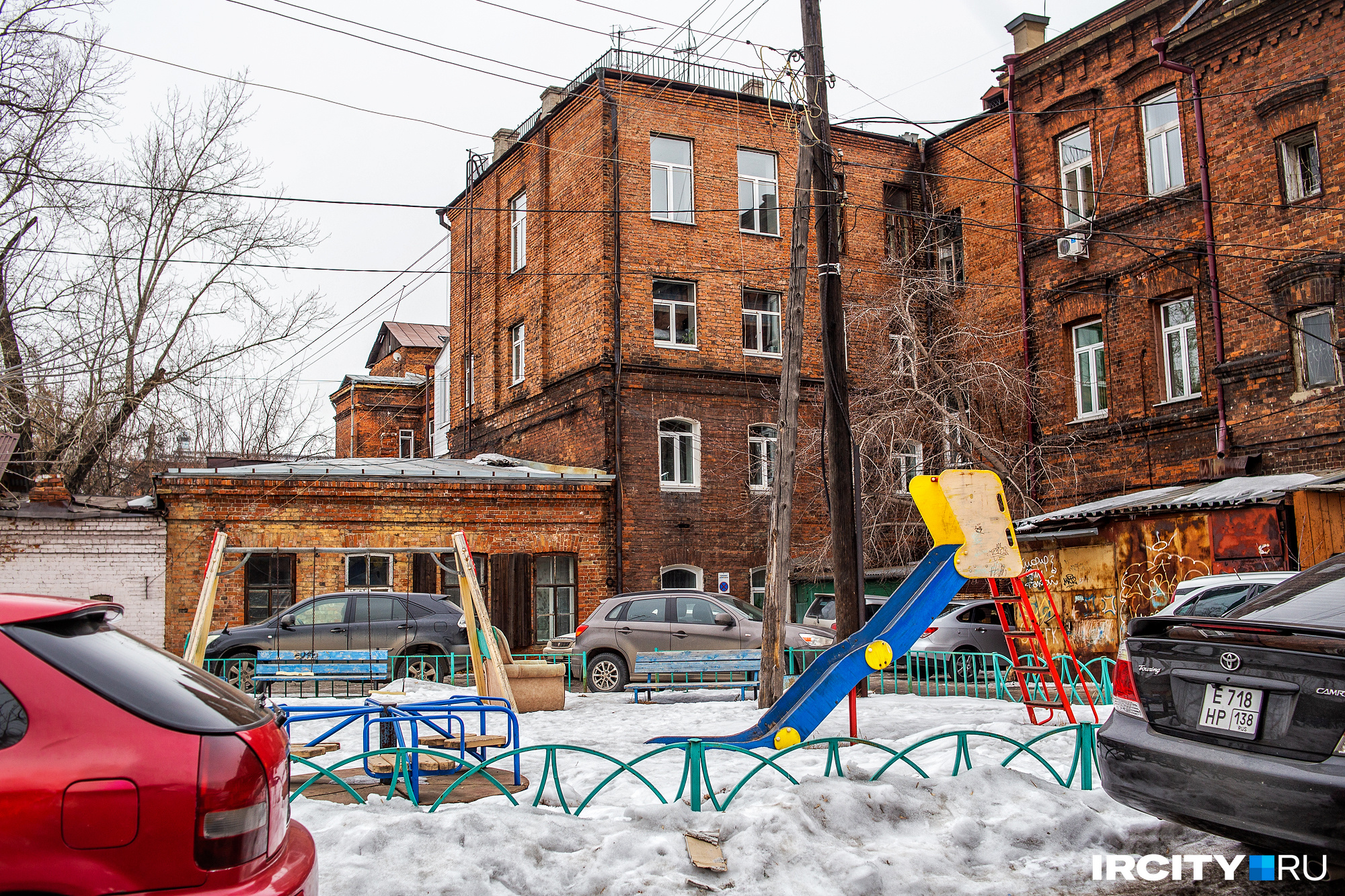 Детская площадка втиснута между автомобилями Детская площадка втиснута между автомобилями