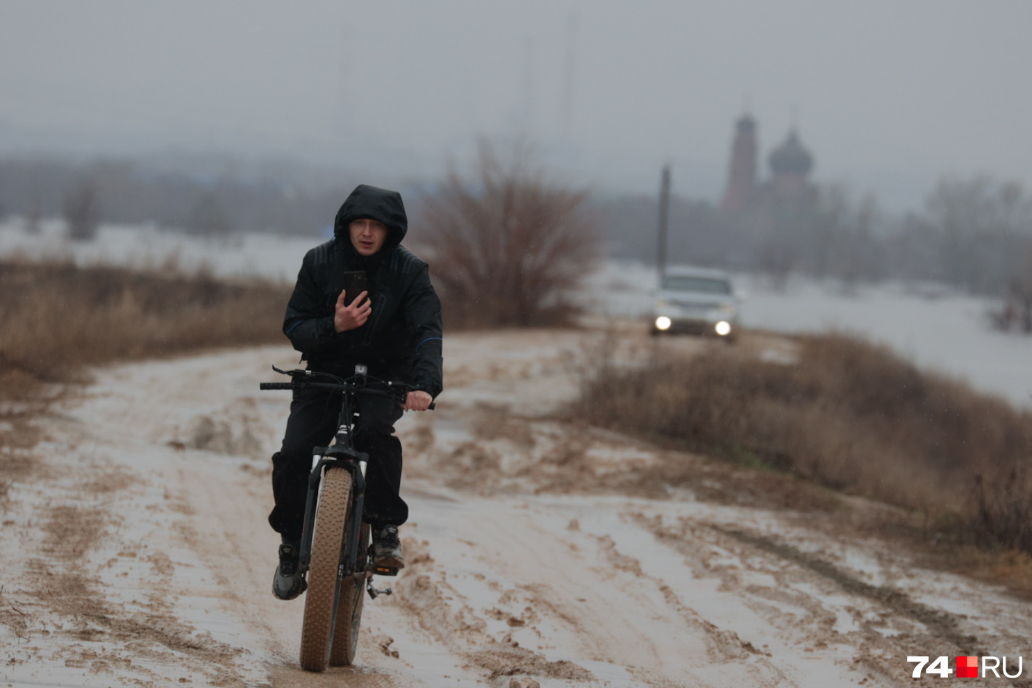 По дамбе парень проезжает на велосипеде из Старого города, где уже затоплены дома