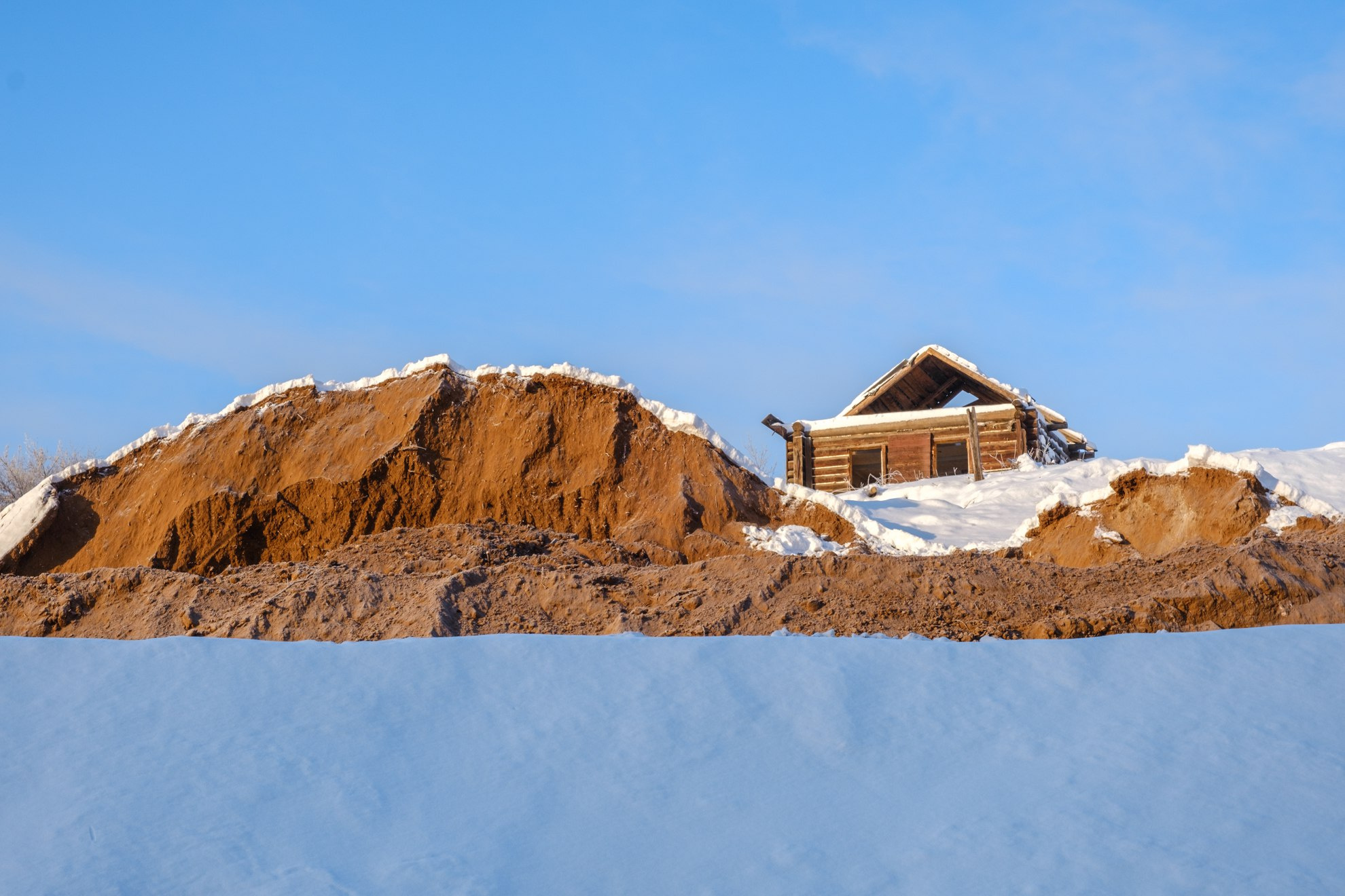 С песчаной горой контрастируют снежные сугробы