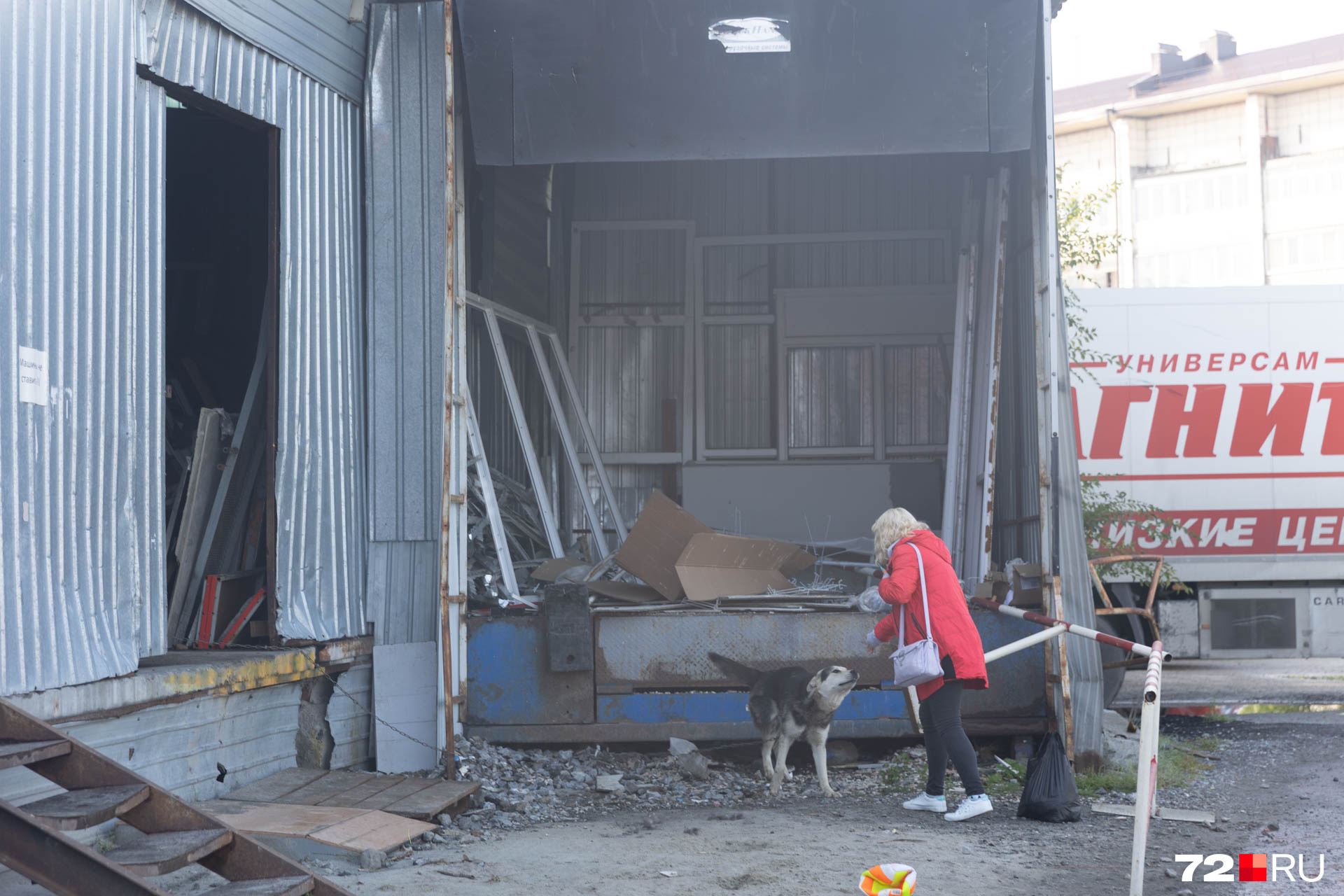 Женщина кормит песика, сторожащего склад рядом с «Тюменским». Собака живет в дыре под конструкцией