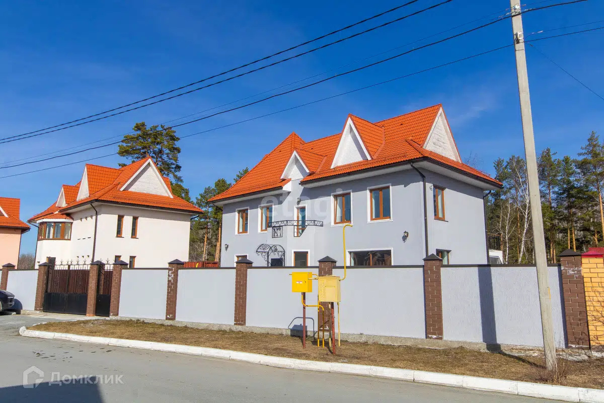 Васильковый фасад дома контрастирует с насыщенной оранжевой кровлей. Этот и соседние дома строили по разработанному для этого коттеджного поселка проекту