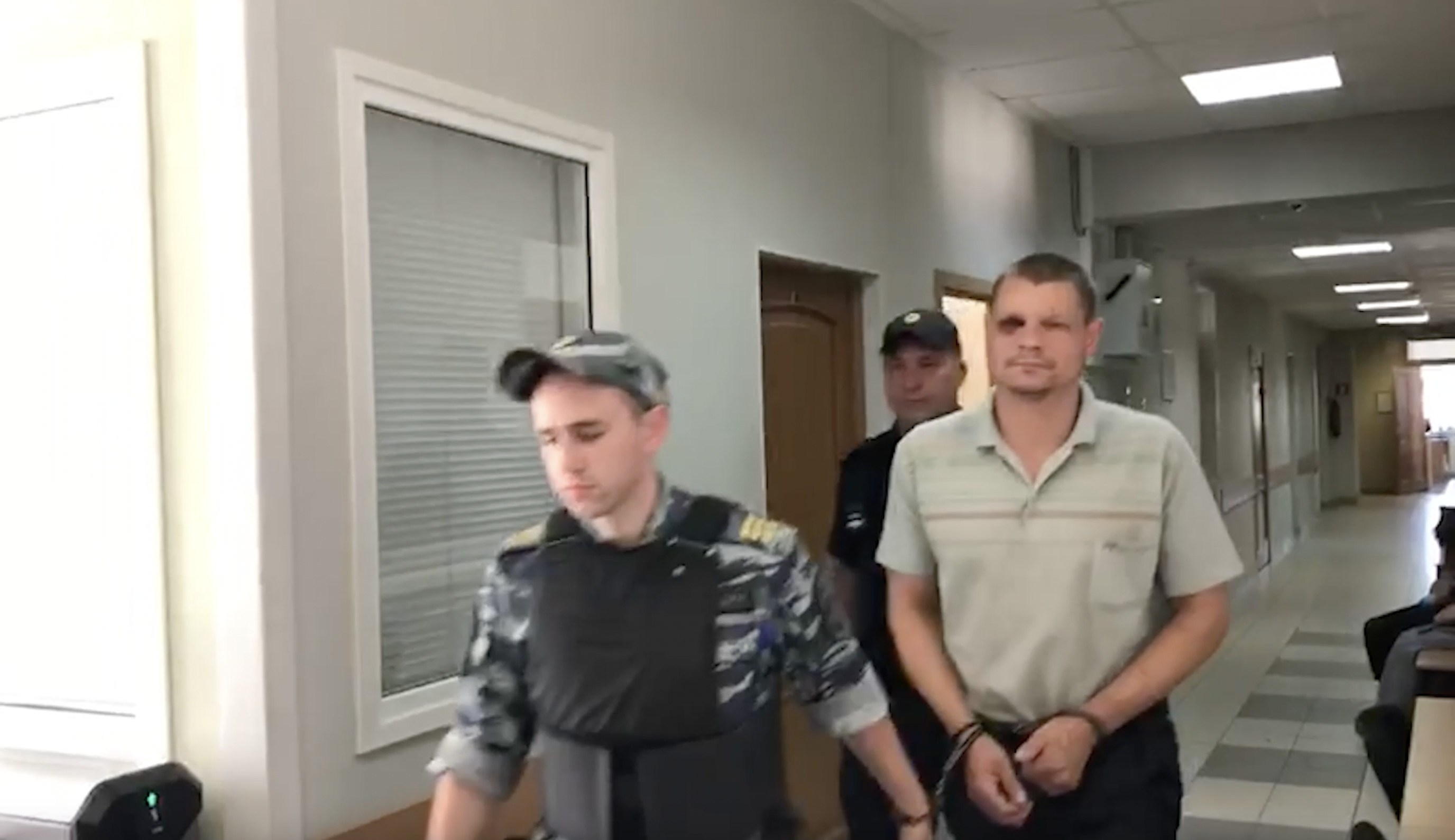 Максима Бочкарëва ведут на суд по избранию меры пресечения. У мужчины подбит глаз. У Софонова рана на лбу