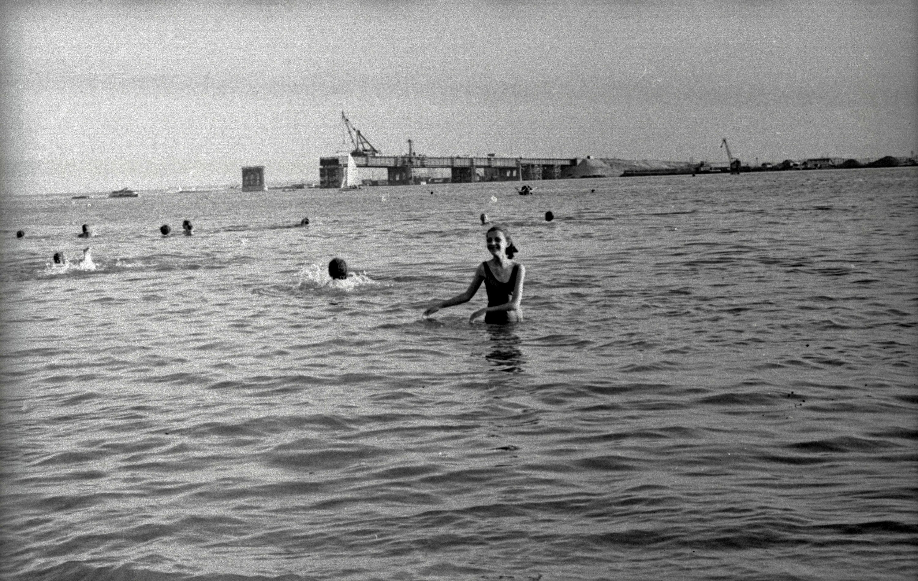 1957 год, хрупкая девушка в слитном купальнике. На фоне видно Ленинградский мост, который еще только строится