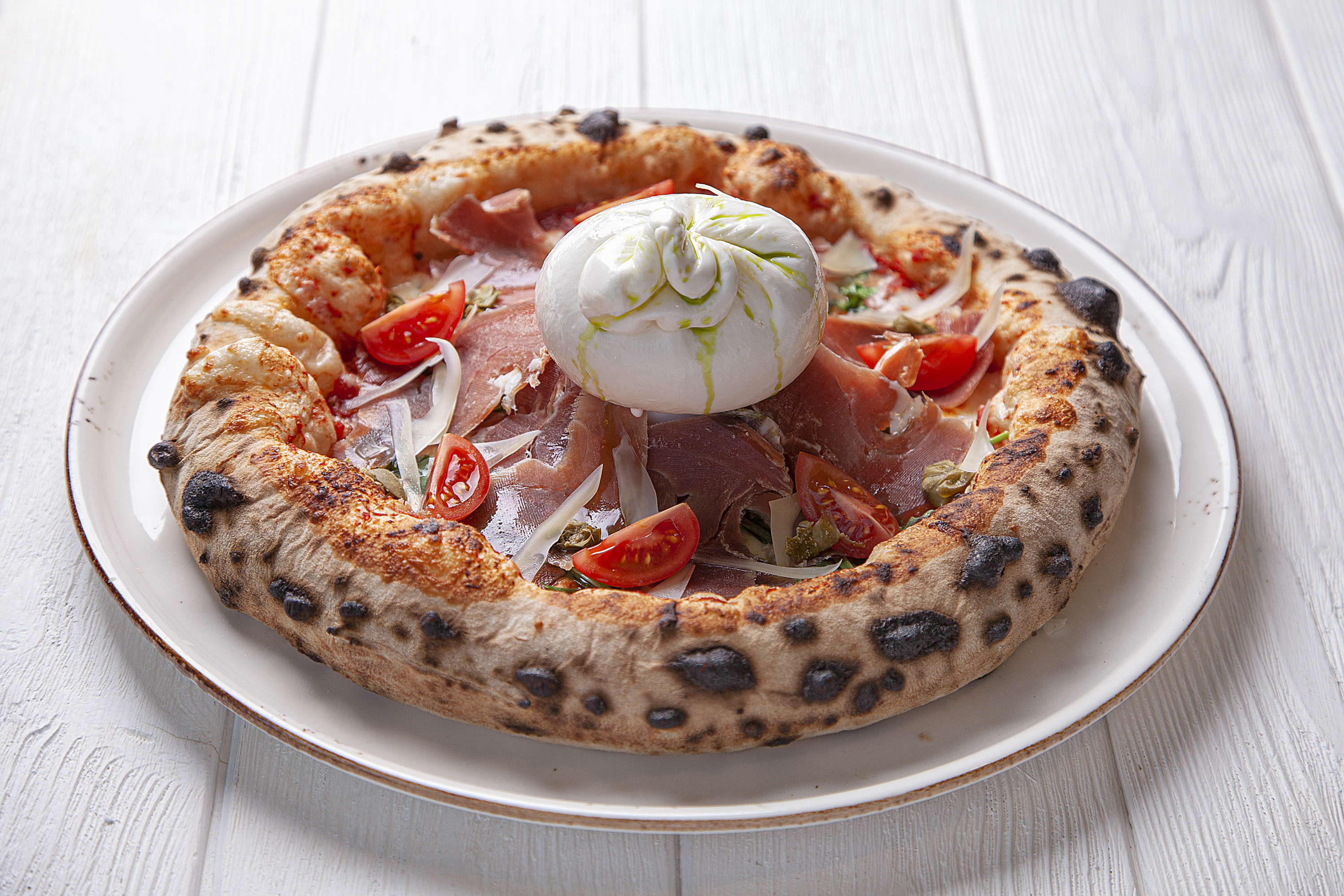 Обязательно попробуйте «Буратту с пармской ветчиной и томатами» — пикантный мясной ингредиент для этой пиццы везут из Италии