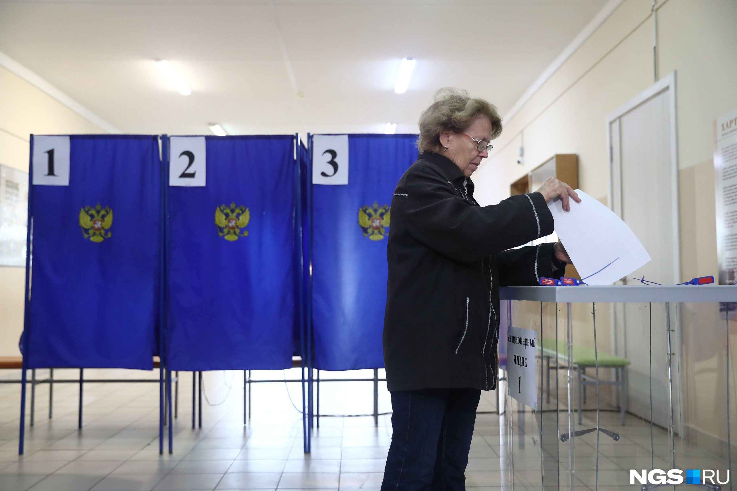 Люди бросают бюллетени в прозрачные урны Люди бросают бюллетени в прозрачные урны