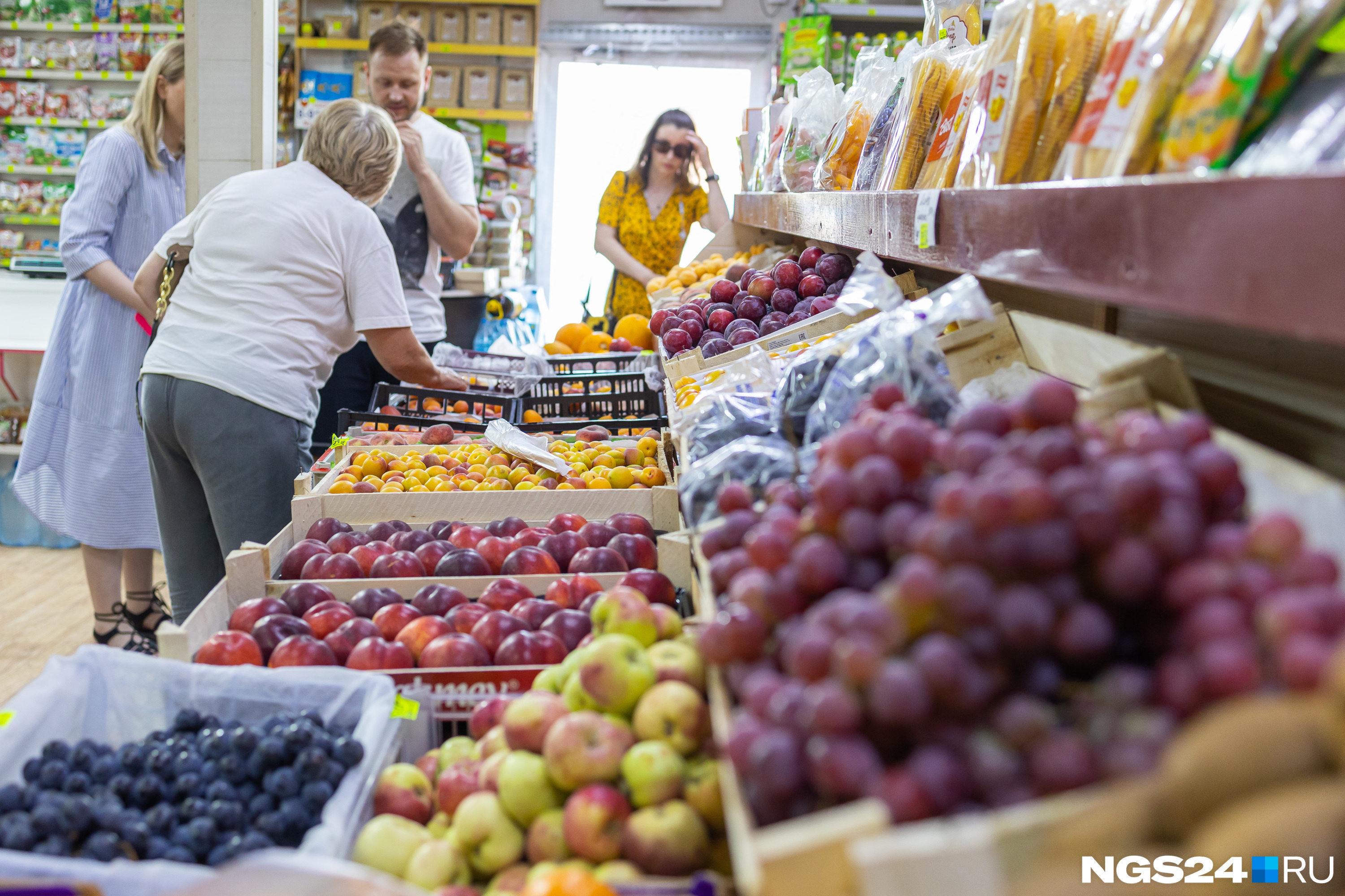 Покупатели кучкуются у корзин с сезонными фруктами