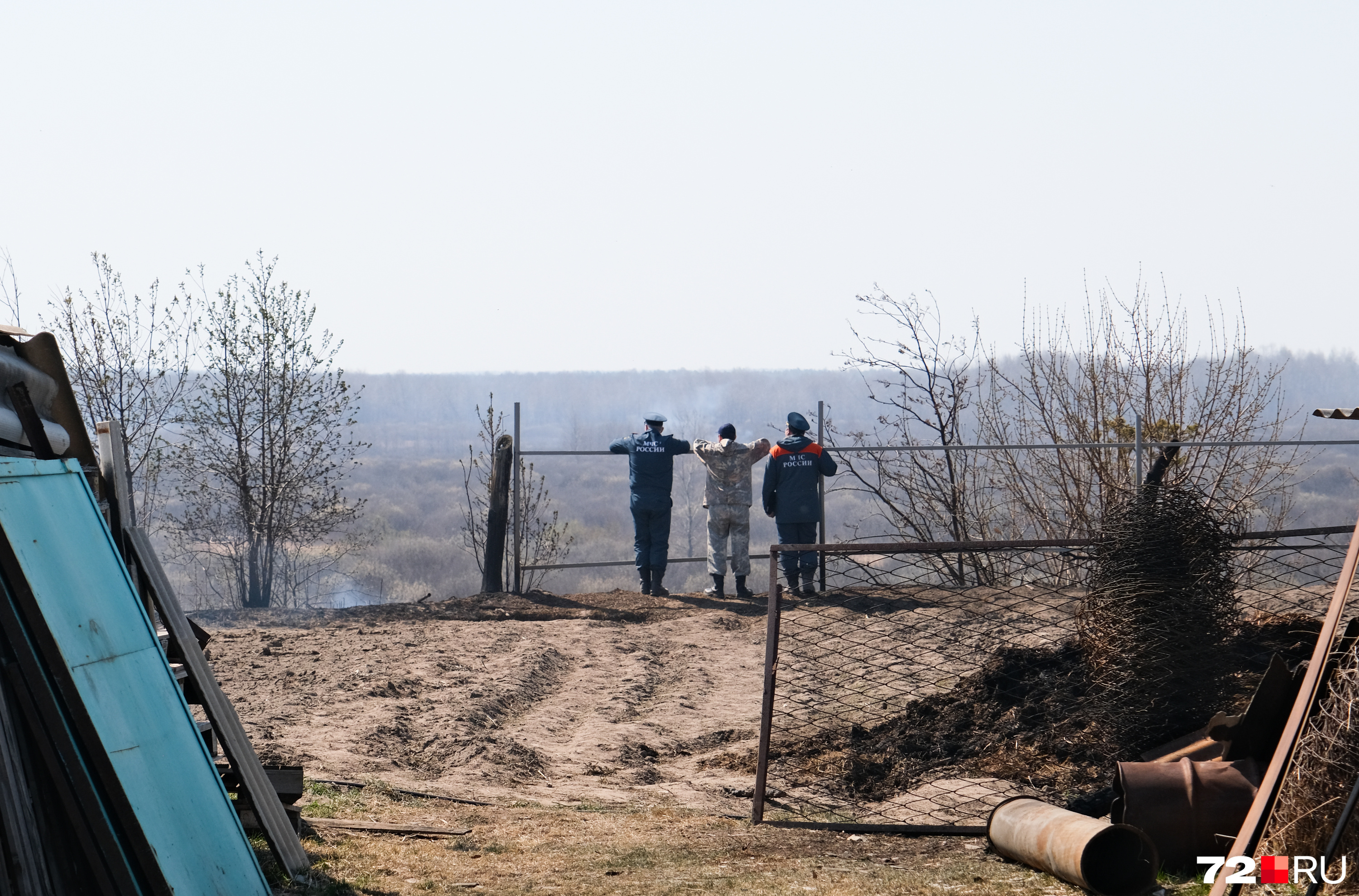 Сотрудники МЧС смотрят на сгоревшие поля