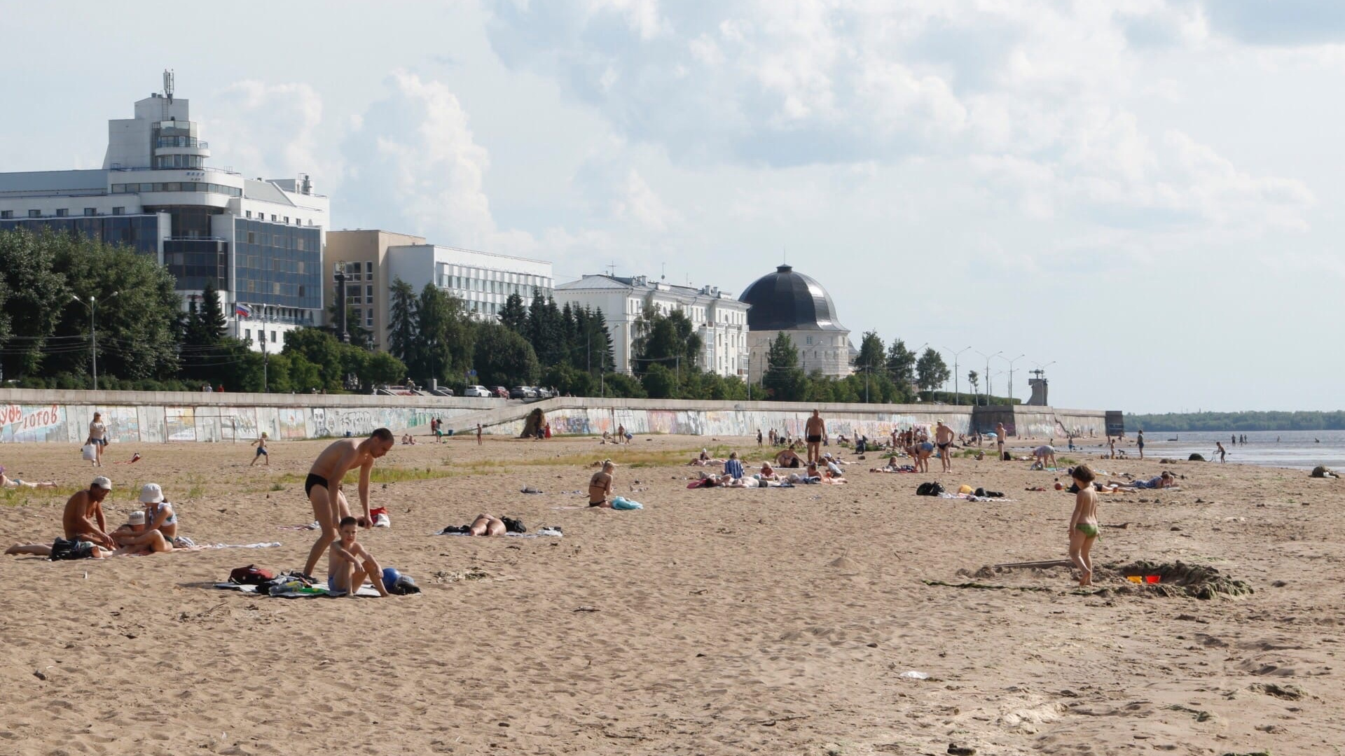 Пляж не благоустроен, но город — курорт! Смотрите, как много горожан загорает у реки в жару